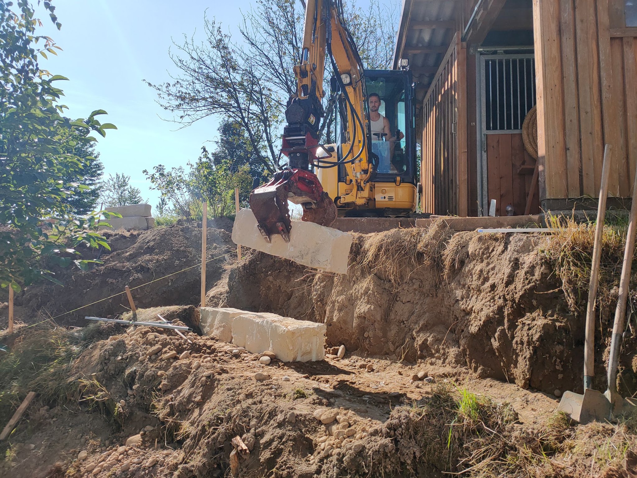 Bagger bei der Terrassierung mit Steinblöcken